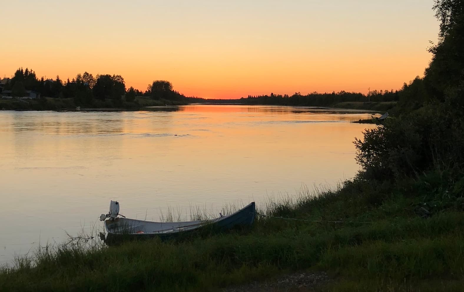 Kvällsljus över älv med båt i förgrunden